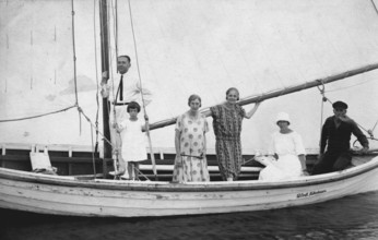 Group in sailing boat, 1920s, family standing on a sailing boat with hoisted sails, historical