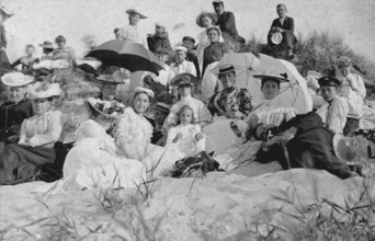 Large group of holidaymakers sitting in dunes, 1910s, Group of woman and men sitting on a sunny