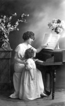 Woman and child with piano, 1920s, Mother and daughter sitting at the piano during music lessons,