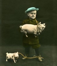 Boy with pigs, 1910s, A boy with a blue hat holds a toy sow and smiles for the photo, Historical