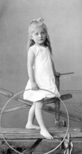 Girl around 1900, Young girl posing with a tyre, barefoot and smiling into the camera, Historical