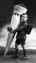 School cone bigger than boy, 1930, A boy carries a large school cone and flowers, ready for his