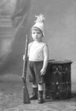 Little boy rifle, 1910s, boy in costume with toy rifle, serious face, vintage studio shot,