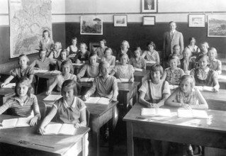 School class girls, 1930s, pupils and teacher in a classroom with maps on the walls, historical