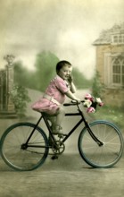 Girl's bicycle, 1910s, Little boy in pink clothes sitting on a bicycle with flower decoration,