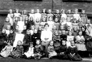 Girls school class, 1910s, Large group of girls with a teacher posing in front of a wall,