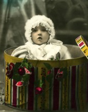 Baby in a gift box, 1930s, A toddler appears from a colourful box surrounded by flowers, Historical