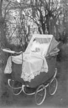 Baby in a pram, 1920s, A baby lies in a nostalgic pram outdoors, surrounded by trees, Historical
