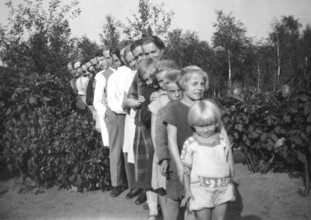 Standing in line, 1920s, family posing in a row in the garden, surrounded by plants, historical