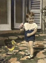 Little boy, 1930s, Boy with plush duck and bouquet of flowers in front of a front door, historical