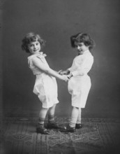 Two small children holding hands, 1920s, Two children holding hands and smiling, black and white