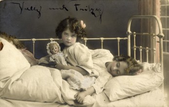 Two girls in bed, 1920s, Two children in bed, one awake with doll, the other asleep, atmospheric,