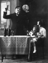 New Year, man raising glass while woman with child sitting at table, old-fashioned photograph,