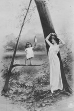 Looking in the mirror, 1920s, A woman and a child holding a hand mirror pose in front of a tree in