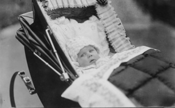 Baby in pram, 1920s, Baby lying in an old-fashioned pram, looking into the camera, black and white,