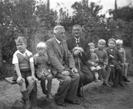 Short and tall men, 1920s, grandfather and children on an outdoor bench, symbolises family ties