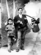 Milkman with apprentice, 1910s, adult and child with pewter cans, standing as father-son pair,