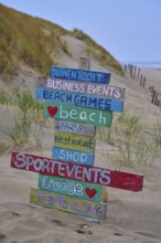 Wooden signs with colourful lettering stand in the dune sand on the beach, beach section 27,