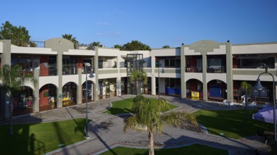Modern shopping centre with arcades, green areas and balconies under sunny skies, Marina Centre,