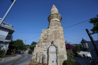 Stone tower and fountain on a street under a blue sky, historical flair, Eski Cami, Minaret, Kos