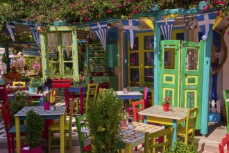 Colourfully decorated taverna with open doors and plants, summery and friendly atmosphere, Platia