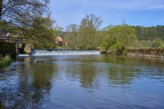 Calm river water in front of a dam wall, surrounded by green nature and blue sky, spring, Obersinn,