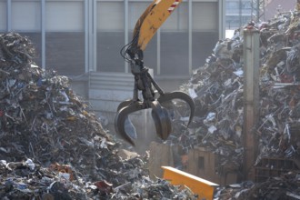 Hydraulic crane lifts scrap metal at the scrap yard