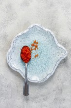 A spoon with orange flying fish caviar, Tobiko, on a light blue plate, caviar for rolls and sushi,