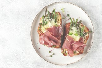 Open sandwiches with asparagus and prosciutto, with cheese, breakfast, on a plate