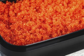 Container with orange caviar, flying fish, Tobiko, on the table, caviar for rolls and sushi,