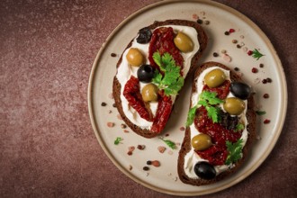 Sandwich with cream cheese, dried tomatoes, olives, breakfast, top view