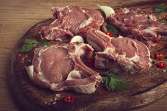 Raw calf meat, meat on the bone, meat for barbecue, cutting board, with spices and herbs, top view