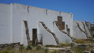 ©Udo Rein, White antique building with exposed stone walls under a blue sky, exterior view, Casa