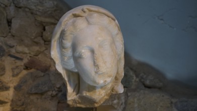 ©Udo Rein, Ancient stone sculpture of a head in front of a rock face, Faustina, Casa Romana, Kos