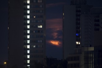 The rising strawberry moon appears between two skyscrapers in Berlin Mitte, Berlin, 11.06.2025