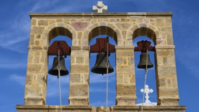 Church of Agios Ioannis Prodromos, Triple bell tower made of stone with blue sky in the background,