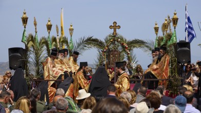 A procession of priests in golden robes, surrounded by palms and religious symbols, holds an