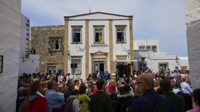 A large crowd gathers in front of a civic building during a civic celebration, Orthodox ceremony,