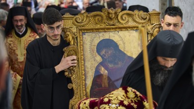 Men in black robes carrying an icon in a golden frame during a procession, Orthodox ceremony, monks
