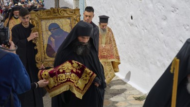 A priest in a black robe leads a procession while another carries an icon, Orthodox ceremony, monks
