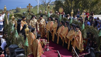 Solemn outdoor religious ceremony with Orthodox priests in gold-decorated robes, surrounded by