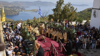 Crowd gathers on a hill overlooking the sea while priests perform a ceremony, Orthodox ceremony,