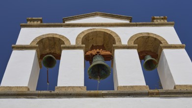 Cross-domed church of Panagia Diasosousan, white bell tower with three bells against a clear sky,