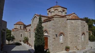 Large stone church building with several domes and a cross in the courtyard, woman's monastery,