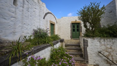 Inner courtyard with whitewashed walls, green doors and flowering plants, Monastery of the