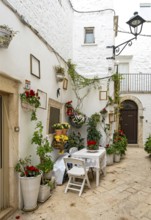 Narrow street with table and chairs in white town of Locorotondo, Apulia - Puglia, Italy