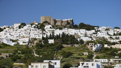 Whitewashed buildings on a green hill with an old castle in the background, Monastery of St John