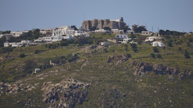 Village on a hill with stone houses and green landscape under a clear sky, Monastery of St John the