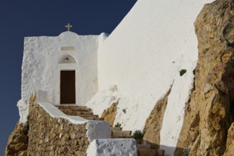 White church on rocky ground with stone steps and cross, under a blue sky, Church of the Prophet