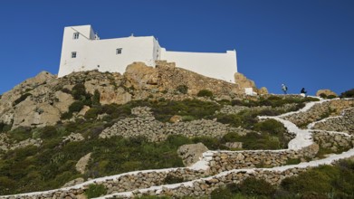 White buildings on a hill with stony paths and abundant vegetation, Church of the Prophet Elias,